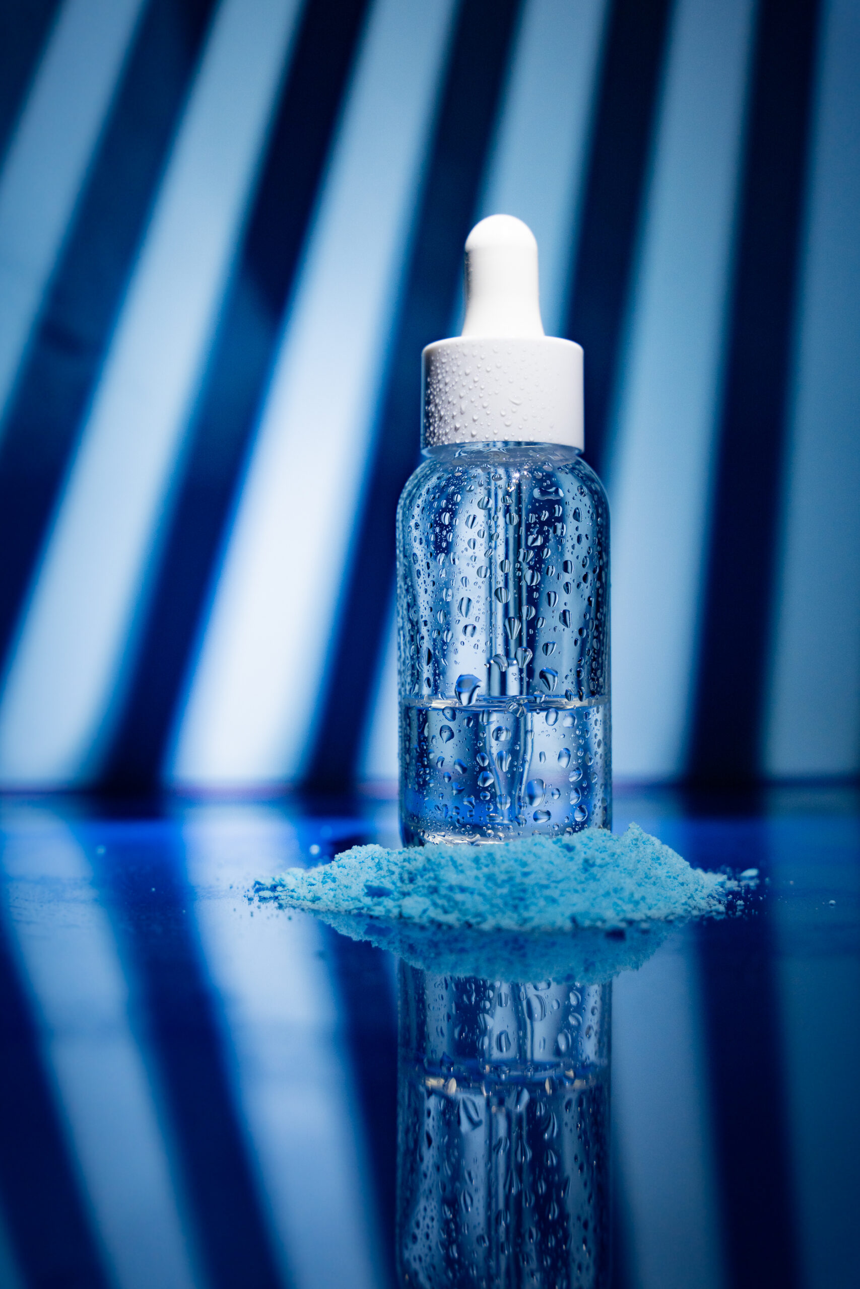 Hochwertige Produktfotografie einer Kosmetik-Glasflasche mit Pipette auf blauem Untergrund – professionelle Businessfotografie in Wien und Niederösterreich