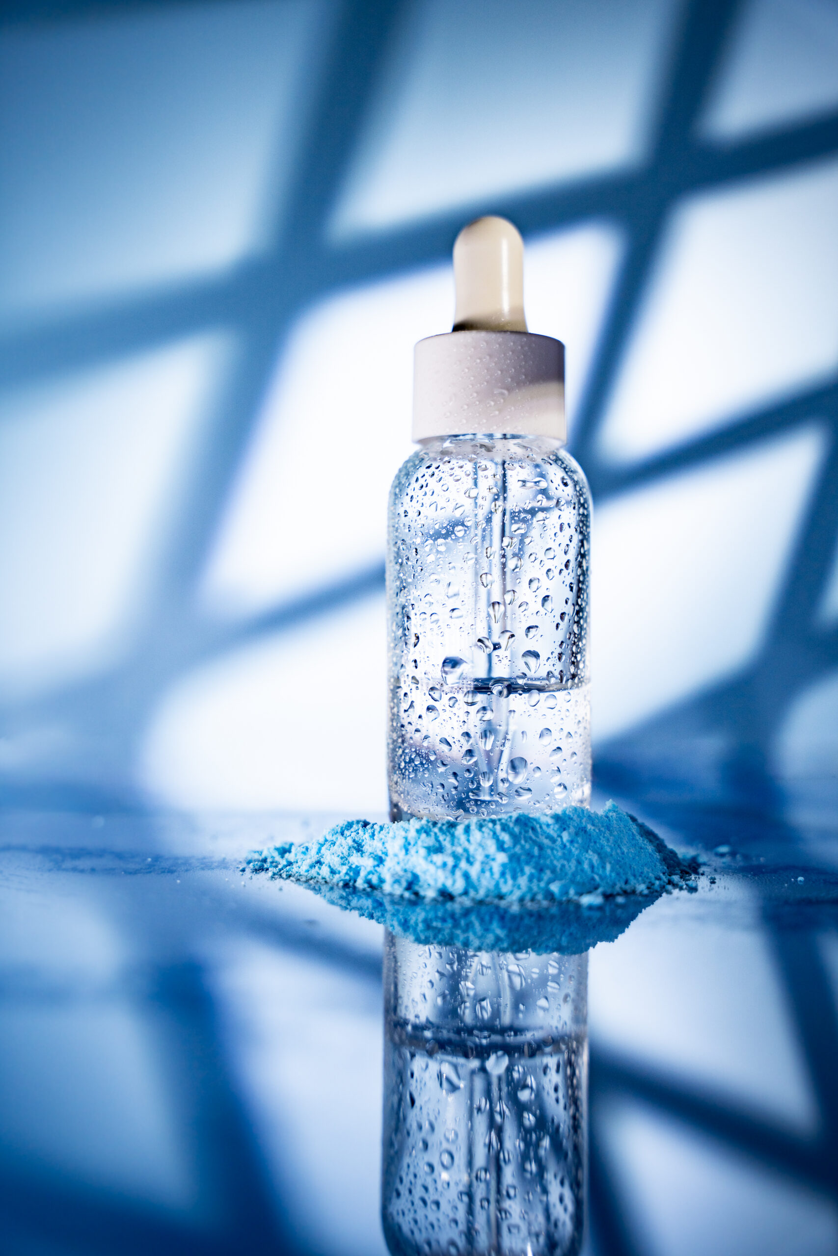 Ästhetische Kosmetik-Produktfotografie mit Glasflasche und Wassertropfen, umgesetzt als moderne Businessfotografie in Niederösterreich